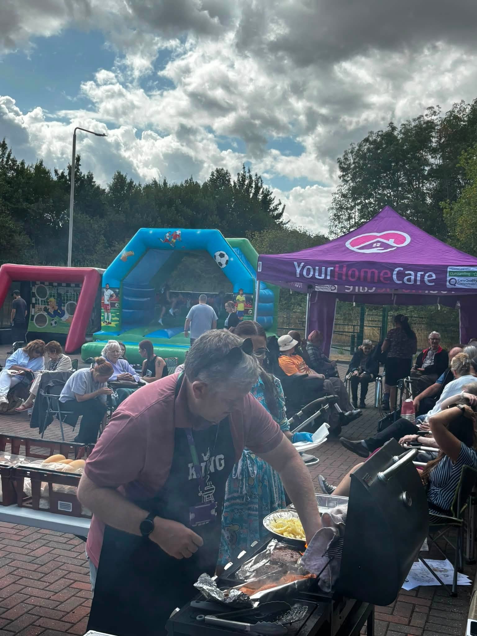 The barbecue being prepared while guests relax together outside